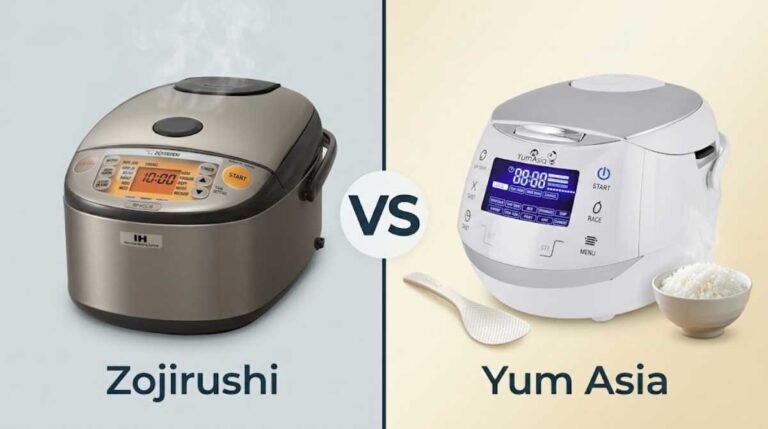 Zojirushi Vs Yum Asia Rice Cooker. A professional side-by-side product photograph on a warm wooden kitchen counter, comparing a stainless-steel Zojirushi Induction Heating rice cooker (left) and a modern white Yum Asia fuzzy logic rice cooker (right). In front of each is a steaming bowl of fluffy white rice. The Zojirushi setup includes a dark slate coaster, a black rice paddle, and a piece of nori seaweed. The Yum Asia setup includes a light bamboo coaster and a small purple orchid. Brand names 'ZOJIRUSHI' and 'YUM ASIA' are printed below their respective cookers